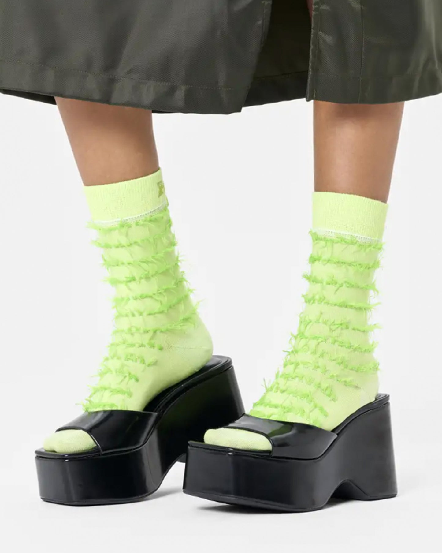 Happy Socks Fringe Sock - Lime green cotton crew length ankle socks with a horizontal fringed pattern in a darker shade, deep cuff, shaped heel and flat toe seam. Worn with black mules and khaki green skirt.