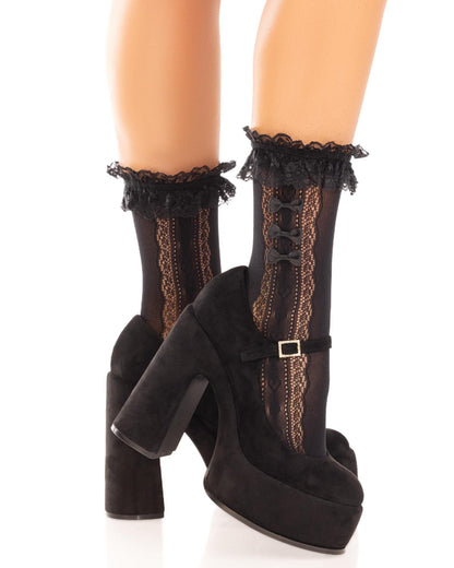 Leg Avenue 3983 Lace Bow Ruffle Heart Sock - Black opaque fashion ankle socks with an open heart lace style side panel with 3 small satin bows on the outside and frilly lace cuff. Side view. Worn with black mary jane high heels.