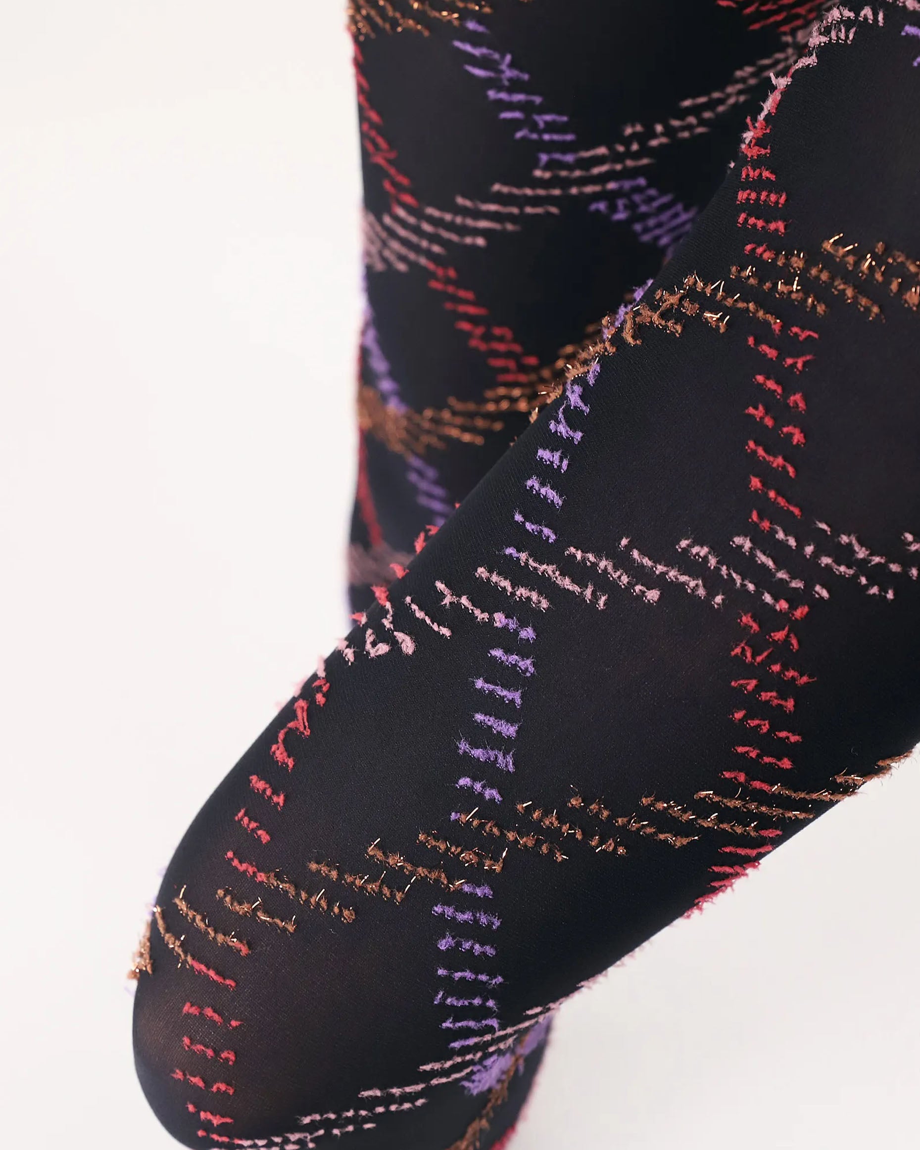 Oroblù Fur Tartan Tights - Black opaque fashion tights with a textured diamond tartan style pattern in purple, red, pale pink and gold. Close up detail of thigh.