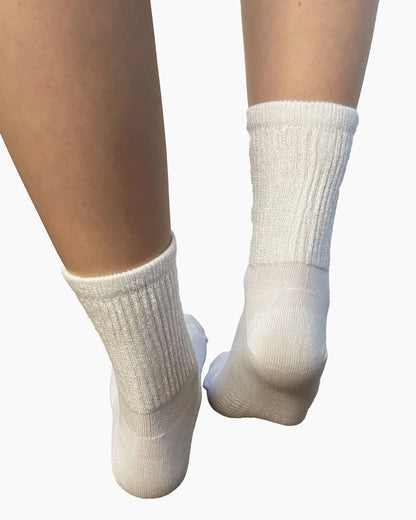 Soft and breathable white bamboo slouch socks with a loose knitted rib top, ankle and foot support and flat toe seams. Back view.