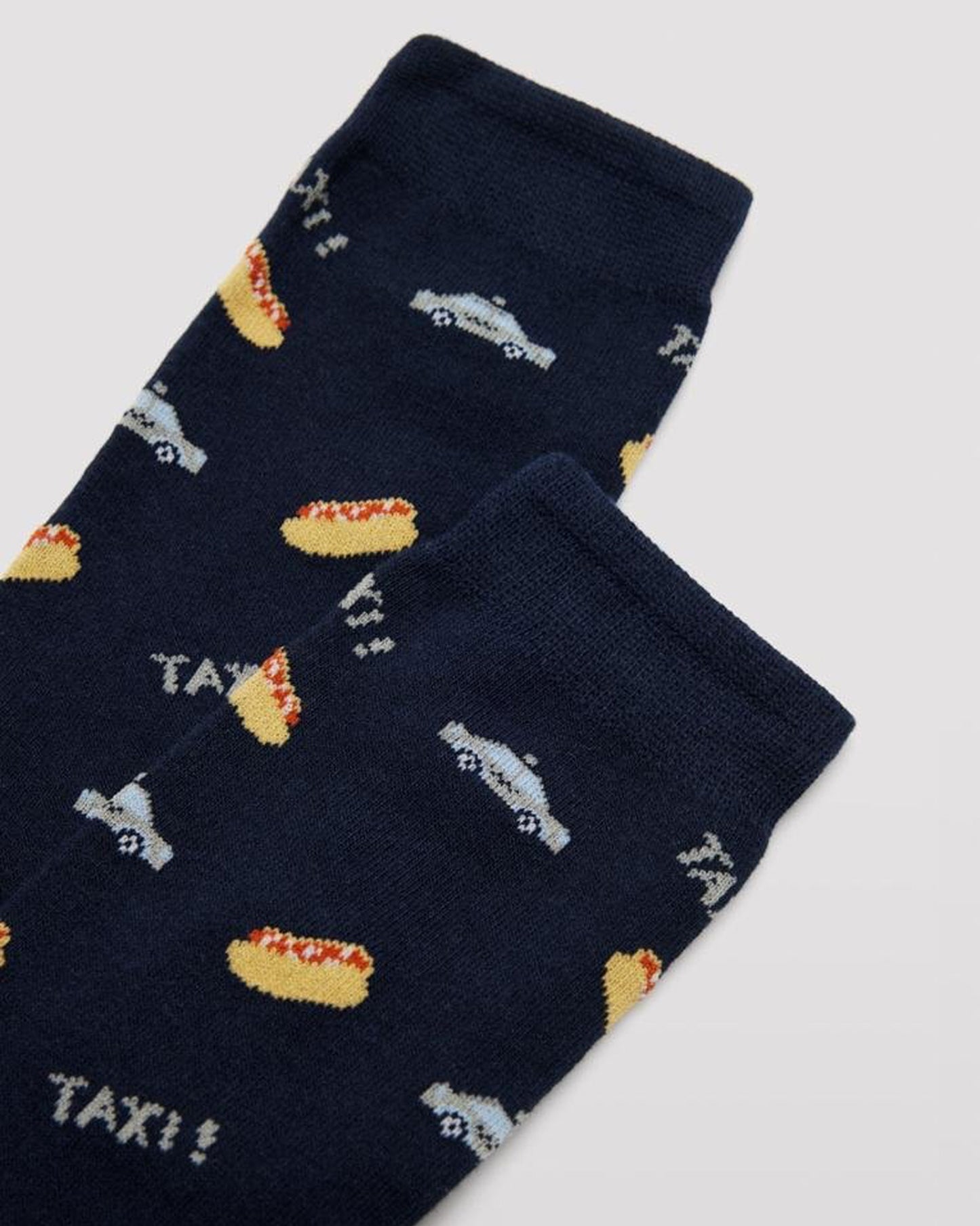 Ysabel Mora 22154 New Yok - Navy cotton crew length ankle socks with an all over pattern of hot dogs and taxis with soft anti-pressure cuffs. Close up detail.