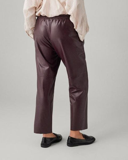 Ysabel Mora 70418 Faux Leather Pants - Loose fitting dark aubergine purple faux leather thermal trousers with side pockets, elasticated waistband, drawstrings, taped leg and soft, warm plush fleece lining. Back view.