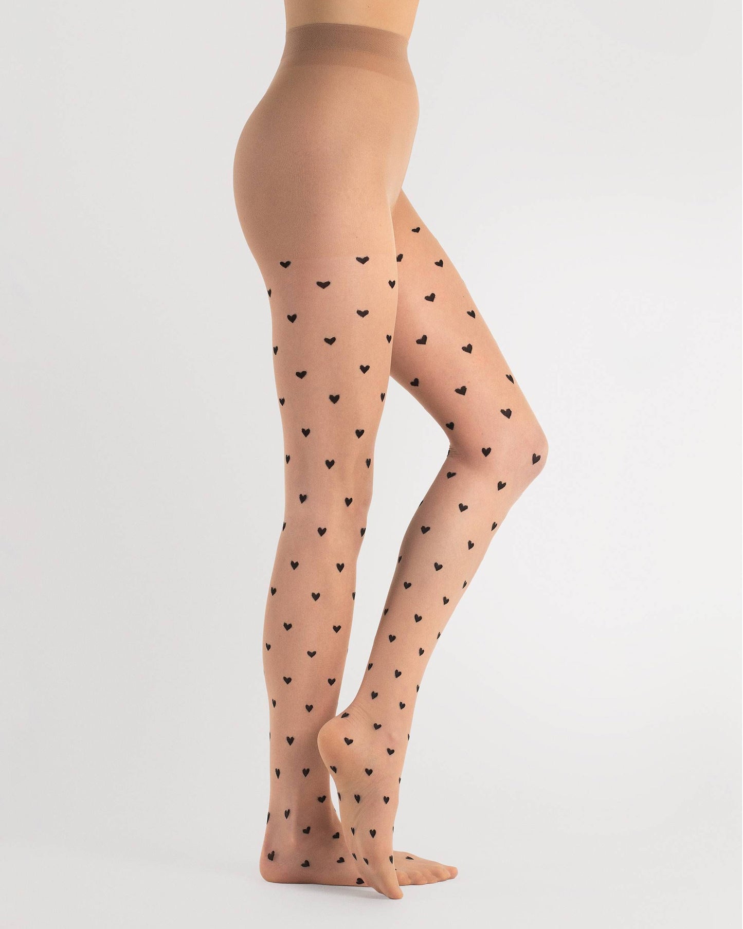 Sheer nude fashion tights with a small black woven heart pattern, invisible reinforced toe and hygienic cotton gusset. Side view.