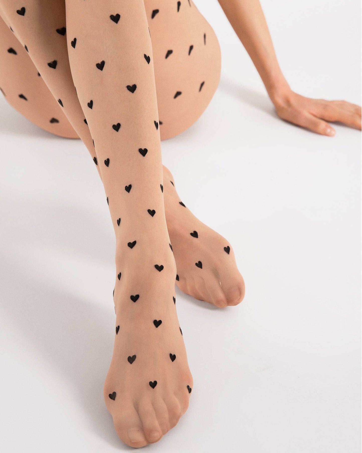 Sheer nude fashion tights with a small black woven heart pattern, invisible reinforced toe and hygienic cotton gusset.